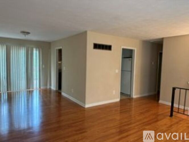 A spacious room with wooden floors and a door on the right.