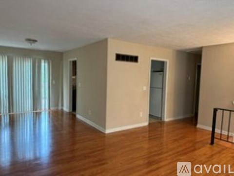 A spacious room with wooden floors and a door on the right.