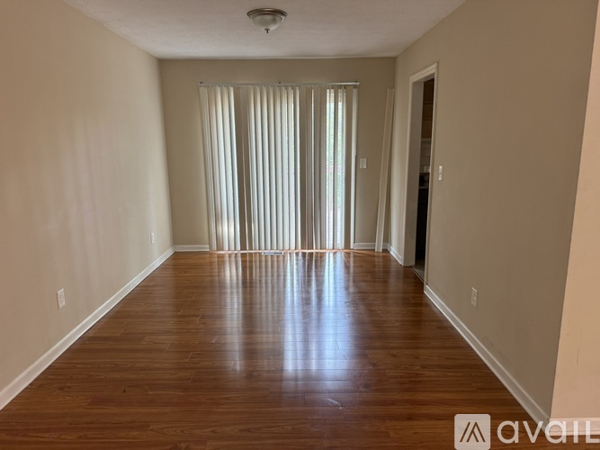 A room with wooden floors and a window with curtains.