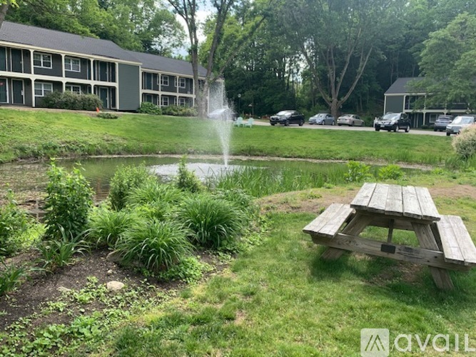 A fountain in the middle of a grassy area with a picnic table in front.