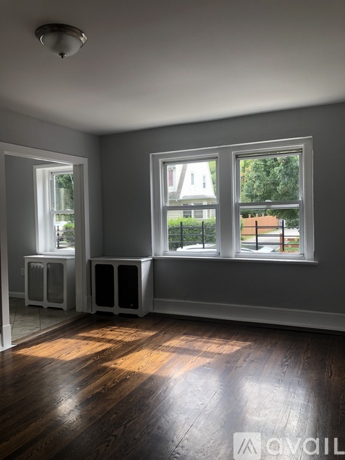 A room with two windows and a wooden floor.