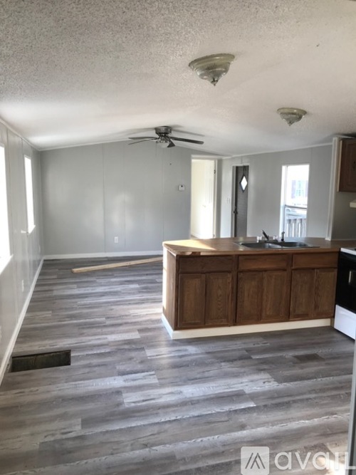 A kitchen with a wooden island and grey wood flooring.