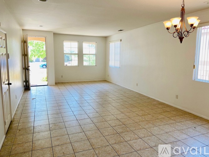 A large, empty room with tiled flooring and a chandelier.