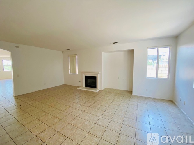 A spacious living room with a fireplace and tiled flooring.