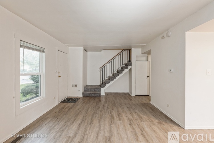 A spacious room with wooden flooring and a staircase leading to another level.
