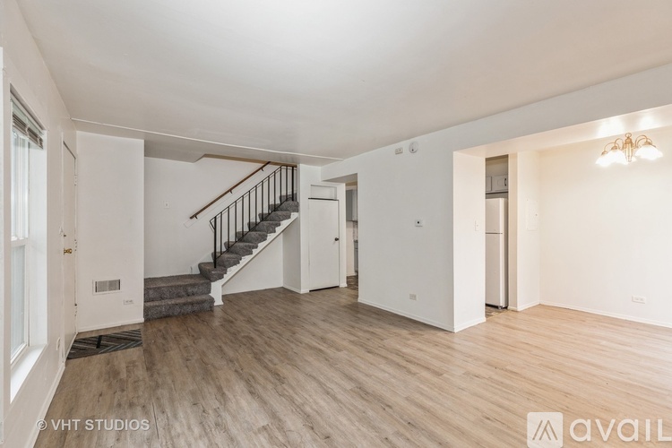 A spacious room with wooden flooring and a staircase leading to another level.