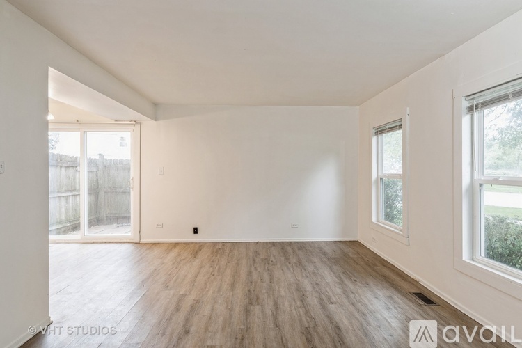 A spacious room with wooden flooring and white walls.