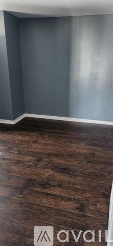 A room with wooden flooring and grey walls.