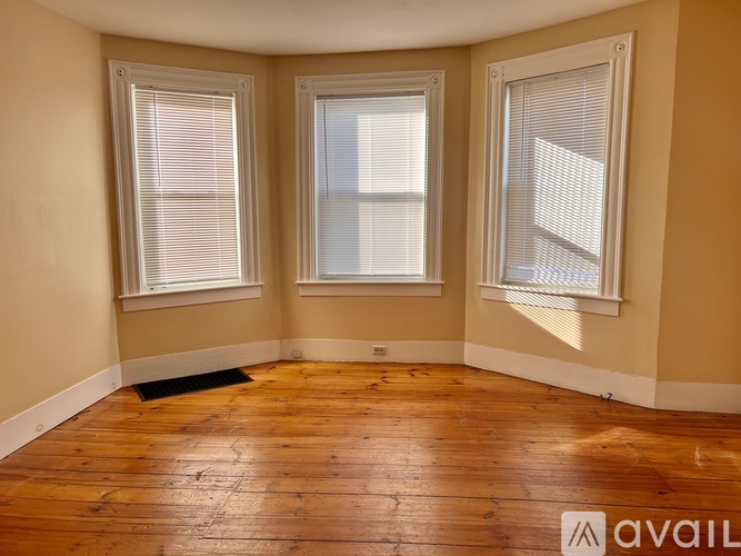 A room with wooden floors and three windows.