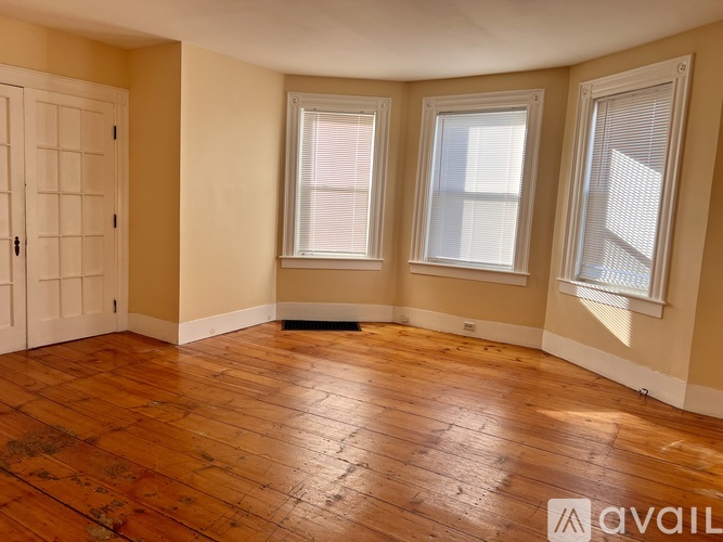 A room with wooden floors and three windows.