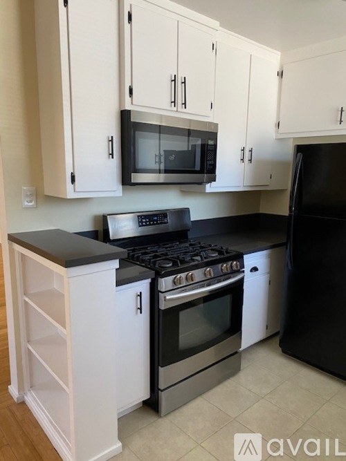 A kitchen with black appliances and white cabinets.