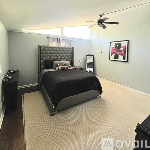 A bedroom with a large bed and a ceiling fan.