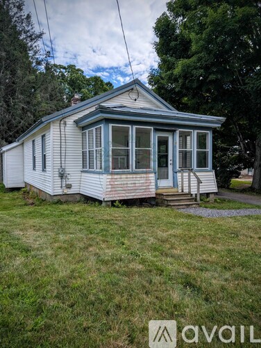 A small house with a porch and a front yard.