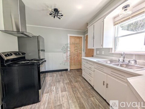 A kitchen with a black stove top oven and white cabinets.