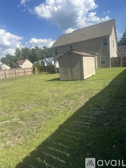 A house with a garage is situated in a grassy area.
