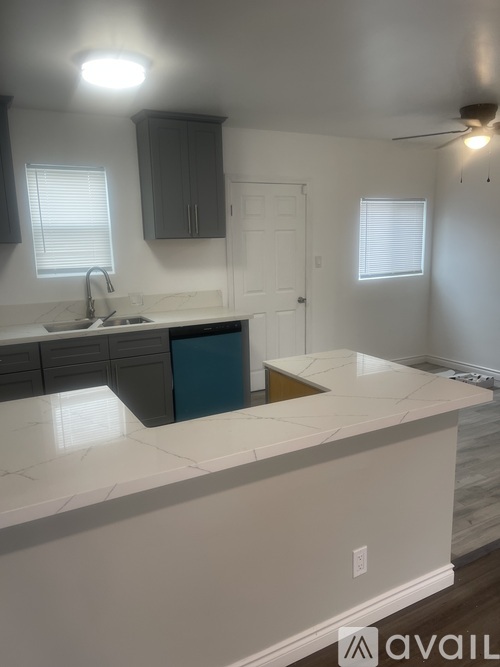A kitchen with a marble countertop and dark brown cabinets.