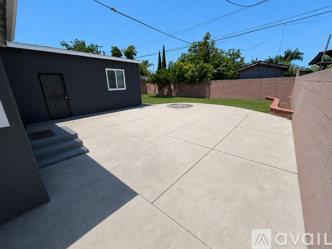 A backyard with a concrete patio and a house with a grey exterior.
