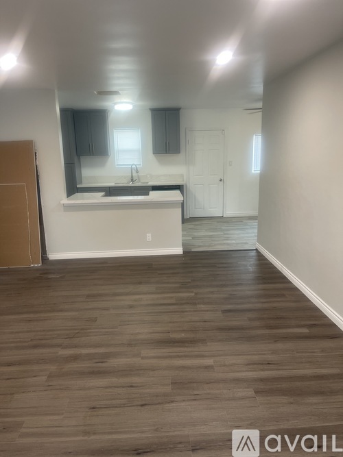 A kitchen with white cabinets and a wooden floor.