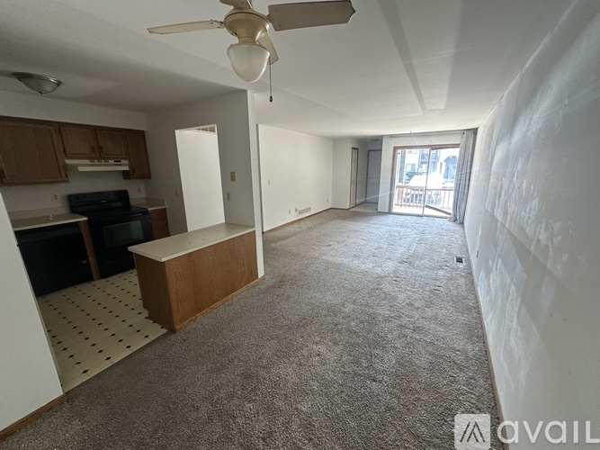 A spacious living area with a ceiling fan and a kitchen with wooden cabinets.