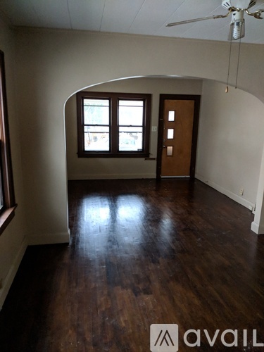 A room with a ceiling fan and wooden floors.