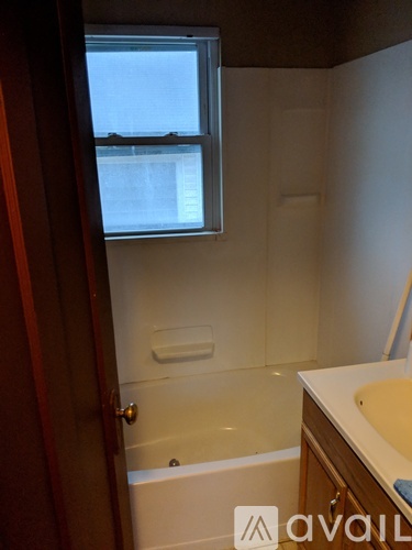 A bathroom with a tub, sink and window.