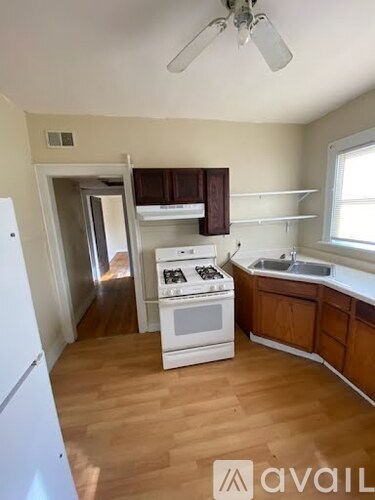 A kitchen with white appliances and wooden floors.