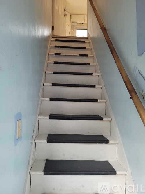 A long flight of stairs with a light switch on the wall.