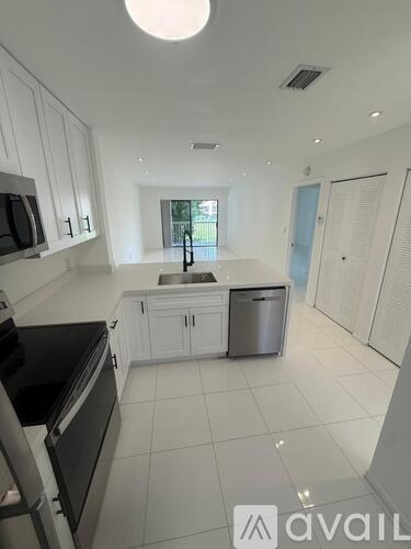 A kitchen with white cabinets and a black fridge.
