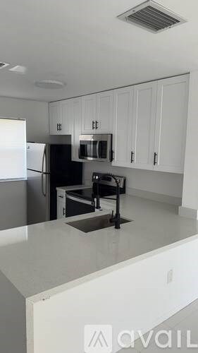A kitchen with white cabinets and a black fridge.