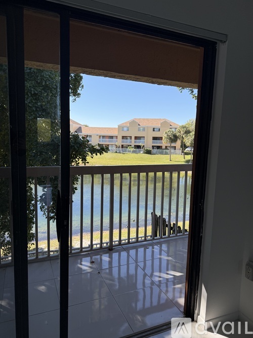 A view from inside a room looking out through a sliding glass door to a pool and apartment complex.