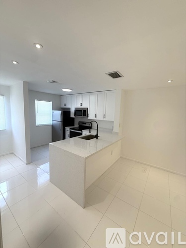 A spacious room with white tiled flooring and a glass door leading outside.