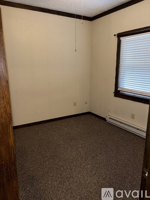 A room with a carpeted floor and a window with blinds.
