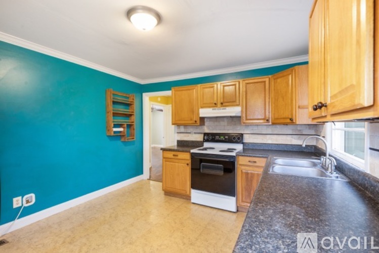 A kitchen with wooden cabinets and a blue wall.