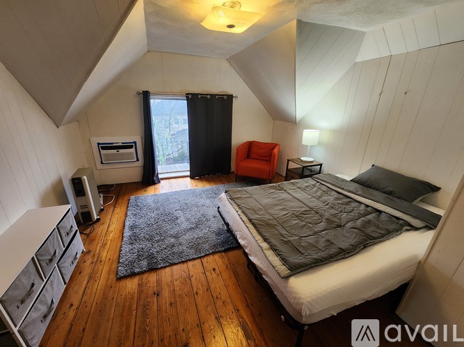 A bedroom with a bed, a chair, and a rug.