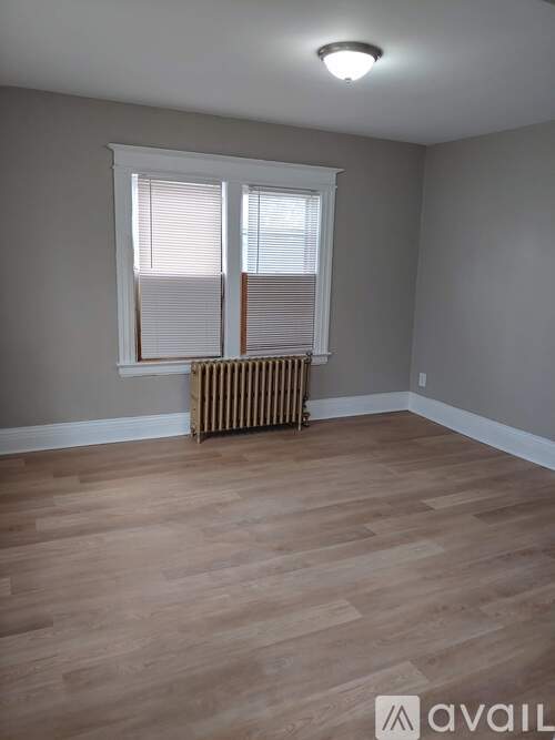 A room with wooden flooring and a window with blinds.
