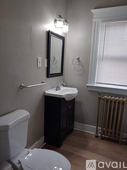A bathroom with a toilet, sink, and mirror.