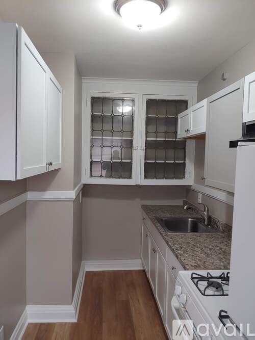 A kitchen with white cabinets and a stove top oven.
