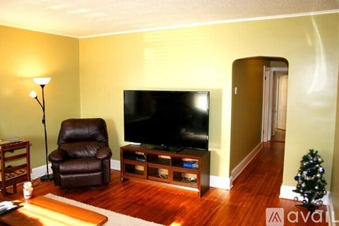 A living room with a brown leather chair and a flat screen TV.