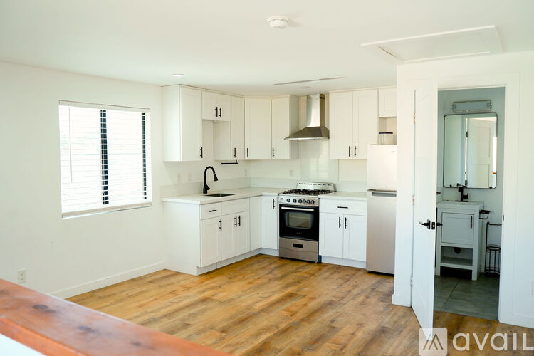 A kitchen with white cabinets and wooden floors.