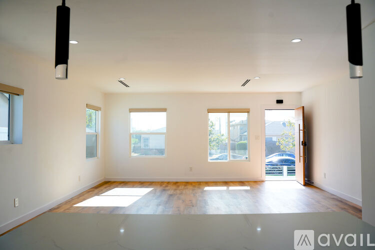 A spacious room with wooden floors and large windows.