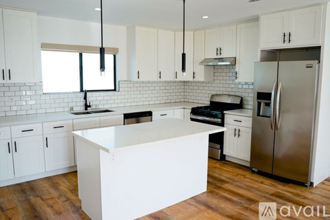 A kitchen with white cabinets and a white island.