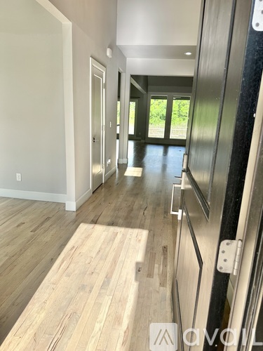 A hallway with wood flooring and a glass door leading to a balcony.