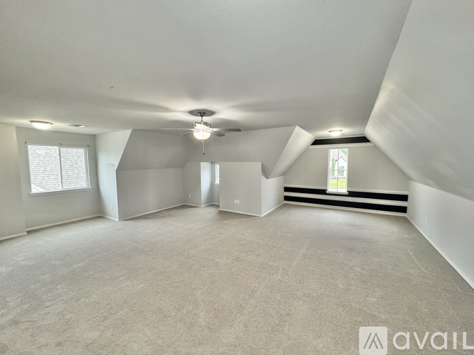 A spacious room with a carpeted floor and a window on the left side.