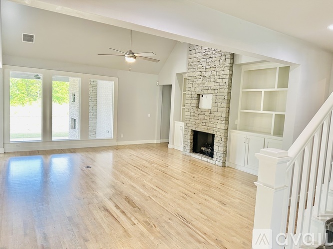 A spacious living room with a fireplace and a staircase.