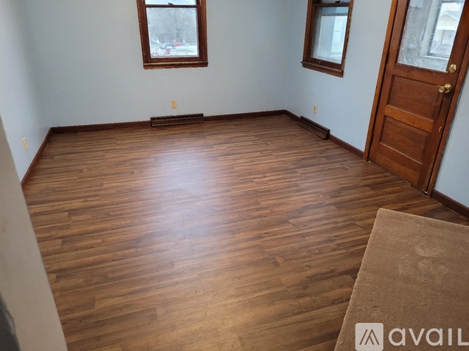 A room with wooden flooring and a door on the right side.