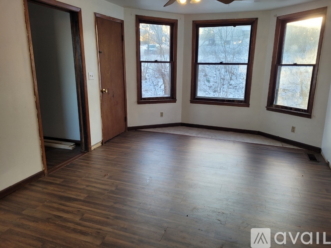 A room with wooden floors and three windows showing a snowy landscape outside.