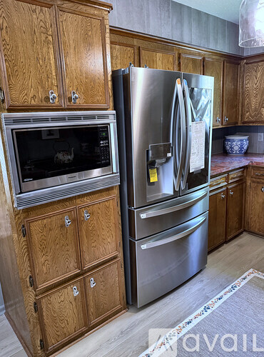 A kitchen with a stainless steel refrigerator and wooden cabinets.