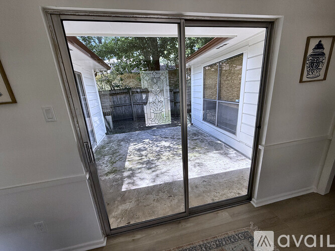 A glass door leading to a backyard with a fence and trees.