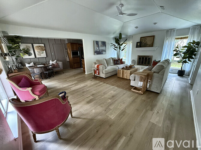 A living room with a pink chair and wooden floors.