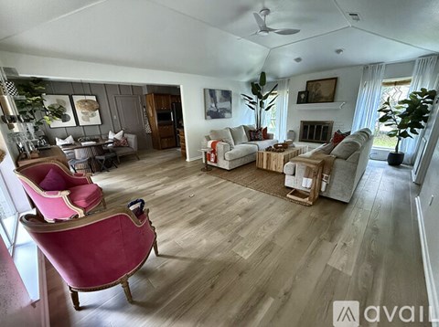 A living room with a pink chair and wooden floors.